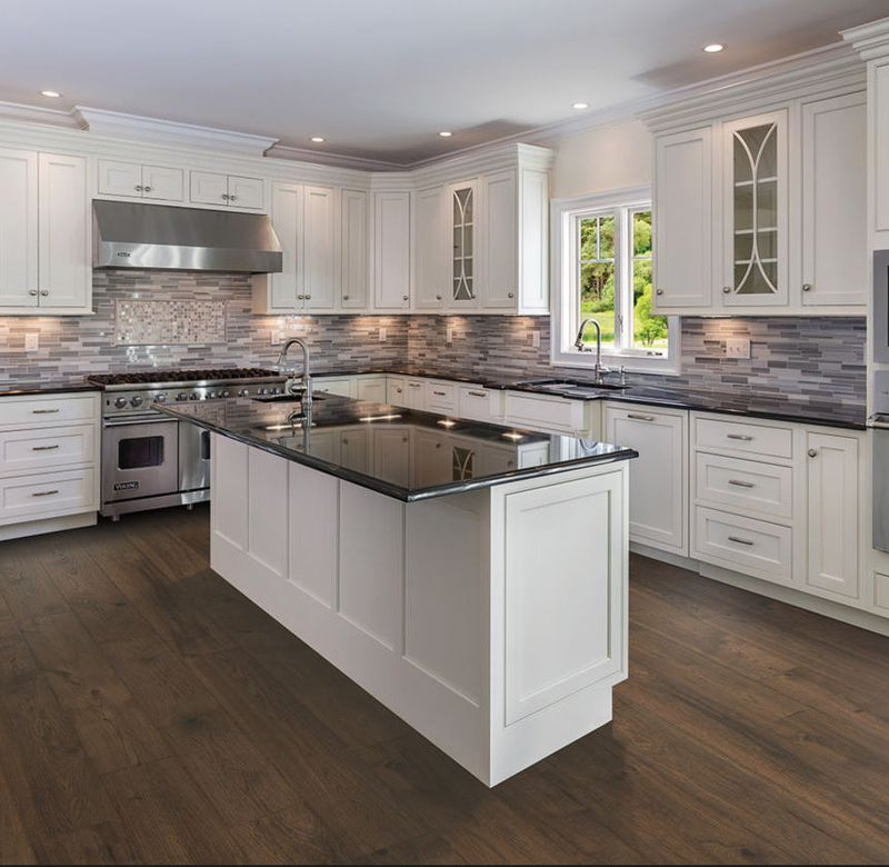 Pergo South Haven Oak LF000891 Waterproof Laminate Flooring - luxury kitchen with earthy rustic tobacco brown knotted wood wide plank floor, white painted cabinets, brushed silver hardware, grey tile backsplash, dark granite counters, and stainless appliances